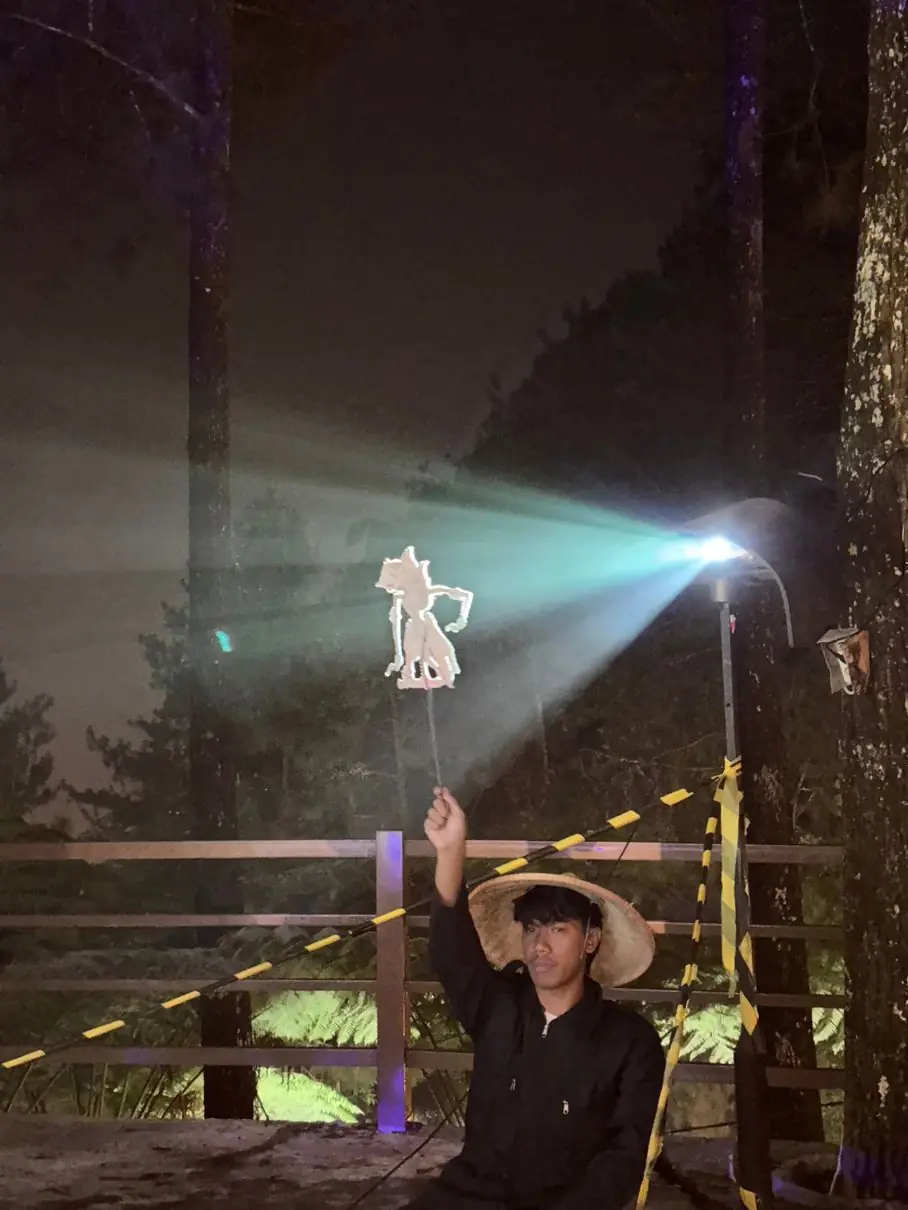 Crew Symforest memainkan wayang di bawah lampu sorot